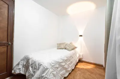 a bedroom with a bed in a white room at Casa grande cerca al Poblado in Medellín