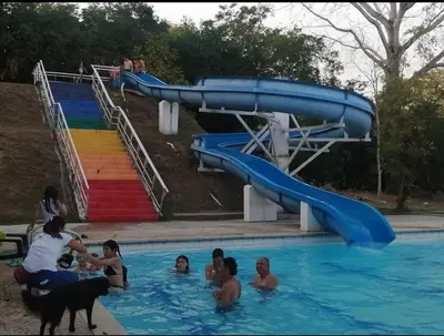 a group of people in a swimming pool with a water slide at Alojamiento Sol Naciente in Puerto Triunfo
