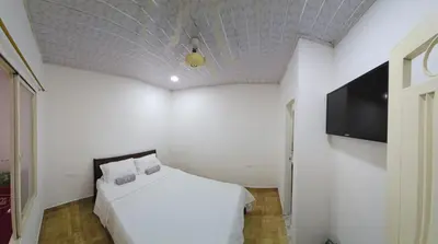 a bedroom with a white bed and a flat screen tv at Alojamiento Sol Naciente in Puerto Triunfo