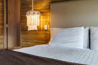 a bedroom with a bed with white sheets and a chandelier at Retreat Villas Llanogrande By CHX in Rionegro