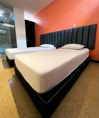 two beds in a room with an orange wall at Hotel Natural Medellin in Medellín