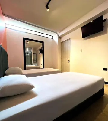 a bedroom with two beds and a large mirror at Hotel Natural Medellin in Medellín