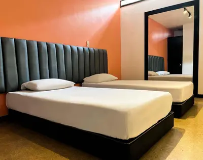 two beds in a room with a mirror at Hotel Natural Medellin in Medellín