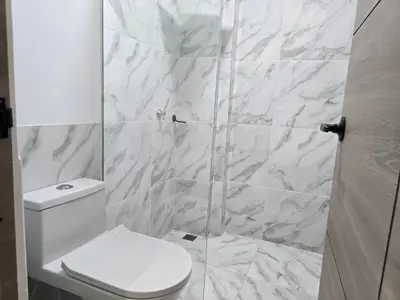 a white bathroom with a toilet and a shower at View Theras Hotel in Doradal