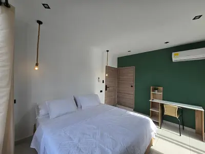 a bedroom with a white bed and a green wall at View Theras Hotel in Doradal