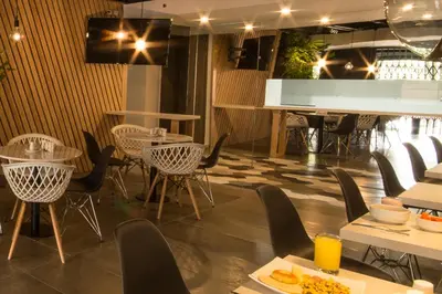 a restaurant with tables and chairs and a piano at Lleras Green Hotel in Medellín