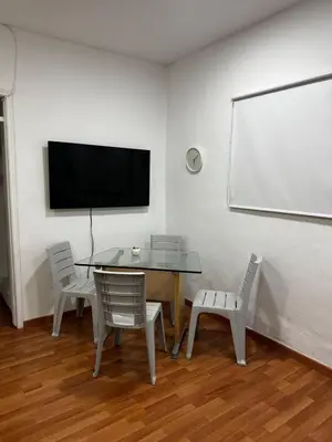 a dining room with a table and chairs and a white wall at Apartamento Rosa colonial in Medellín