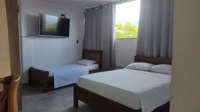 a bedroom with two beds and a tv on the wall at Apartamento con jacuzzi in Santa Fe de Antioquia