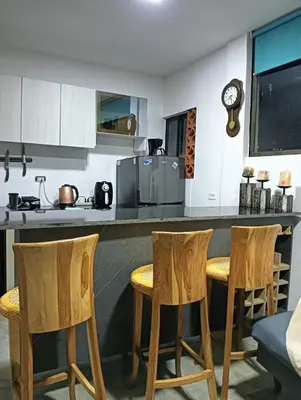 a kitchen with wooden bar stools and a counter at Apartamento con jacuzzi in Santa Fe de Antioquia