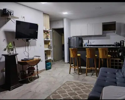 a living room with a couch and a kitchen with a tv at Apartamento con jacuzzi in Santa Fe de Antioquia
