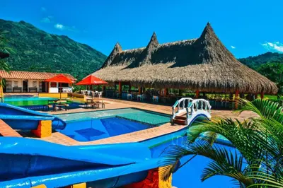 a resort with a swimming pool and a straw hut at Hotel Hacienda La Bonita in Amagá