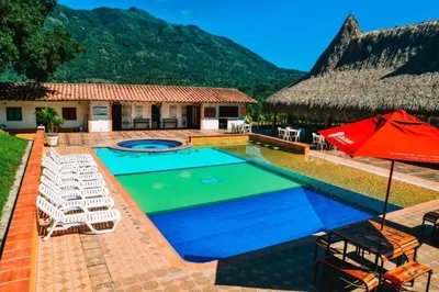 a resort with a pool with chairs and an umbrella at Hotel Hacienda La Bonita in Amagá