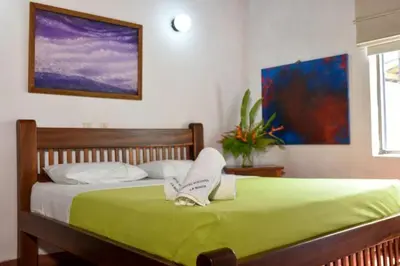 a bedroom with a green bed with towels on it at Hotel Hacienda La Bonita in Amagá