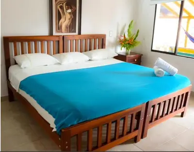 a bedroom with a large bed with a blue blanket at Hotel Hacienda La Bonita in Amagá