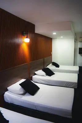 a room with three beds with white sheets and black pillows at Hotel Santorini la 70 in Medellín