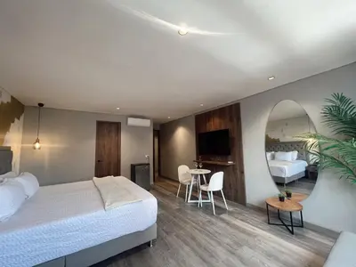 a bedroom with a bed and a table and a mirror at SUITE DE LUJO FARO con Aire Acondicionado y Coworking in Medellín