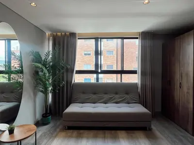 a living room with a couch and a large window at SUITE DE LUJO FARO con Aire Acondicionado y Coworking in Medellín