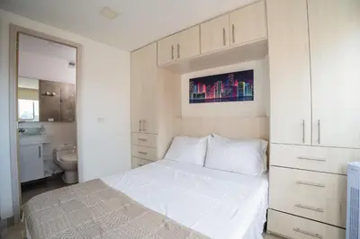 a bedroom with a white bed and a bathroom at Cozy apt in Poblado The best area Great view in Medellín