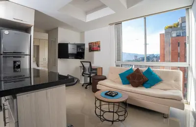 a living room with a couch and a kitchen at Cozy apt in Poblado The best area Great view in Medellín