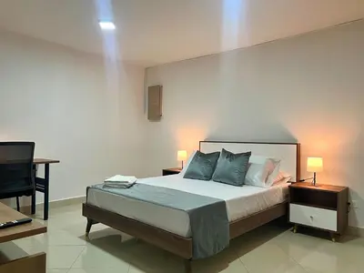 a bedroom with a bed with two lamps and a desk at Comfortable and equipped apartment 5 minutes from the 70 Laureles in Medellín