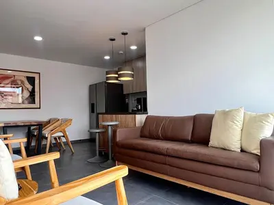 a living room with a brown couch and a table at Moderno Apartamento Sabaneta - Century Tower II in Sabaneta