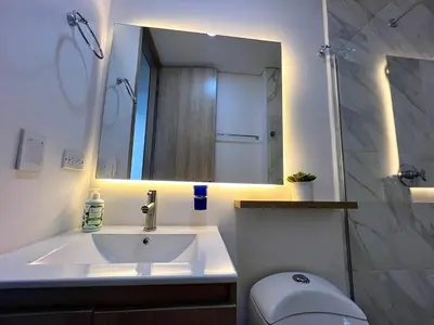 a bathroom with a sink and a toilet and a mirror at Moderno Apartamento Sabaneta - Century Tower II in Sabaneta