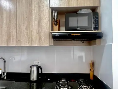 a kitchen with a microwave over a stove top at Moderno Apartamento Sabaneta - Century Tower II in Sabaneta