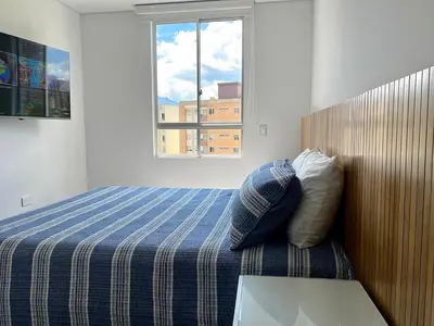 a bedroom with a bed with a blue and white blanket at Moderno Apartamento Sabaneta - Century Tower II in Sabaneta
