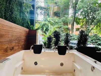 a bath tub in front of a window with plants at Casa Amsterdam with Jacuzzi in Poblado Medellín in Medellín