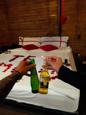 two people holding beer bottles on a bed at Gampling el Cielo los pinos in Rionegro
