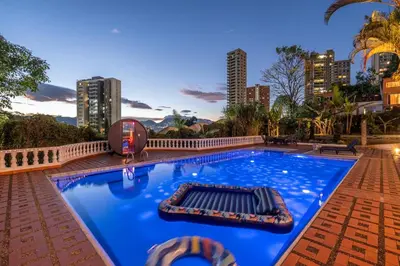 a large blue swimming pool with a city skyline in the background at Pool, Views, Sauna, Bar, Fire Pit and 24 HR Security in Medellín