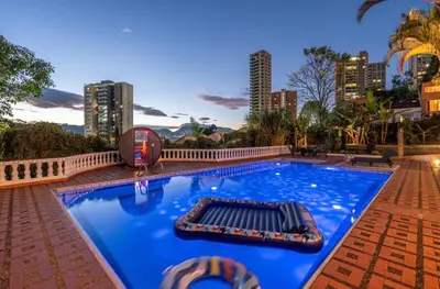 a large blue swimming pool with a city in the background at Pool, Views, Sauna, Bar, Fire Pit and 24 HR Security in Medellín