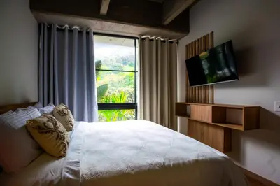 a bedroom with a bed with a television and a window at Home away from home - By Adri in Envigado