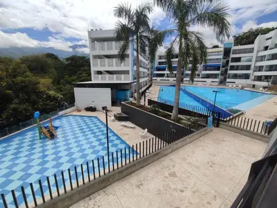 a swimming pool with palm trees and a building at San Jeronimo - Apartamento - Hospedaje in San Jerónimo