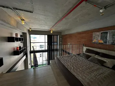 a bedroom with a bed and a brick wall at Central Medellin Modern Loft - Balcony and Transit in Medellín