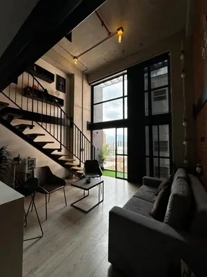 a living room with a couch and a staircase at Central Medellin Modern Loft - Balcony and Transit in Medellín