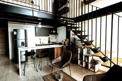 a kitchen with a staircase leading up to a loft at Central Medellin Modern Loft - Balcony and Transit in Medellín