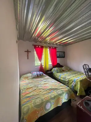 two beds in a room with a cross on the wall at CASA FINCA San Rque Antioquia in San Roque