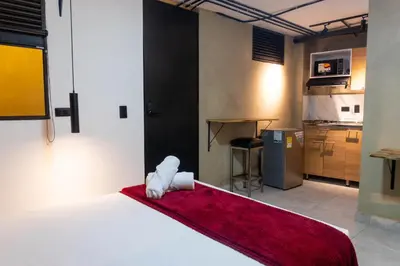 a bedroom with a white bed with a red blanket at hotel civitas medellin in Medellín