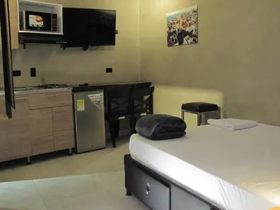 a room with two beds and a kitchen with a tv at hotel civitas medellin in Medellín