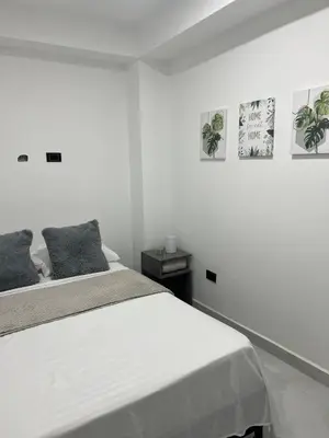 a white bedroom with a bed and some pictures on the wall at Apartamento en La America 2 habitaciones in Medellín