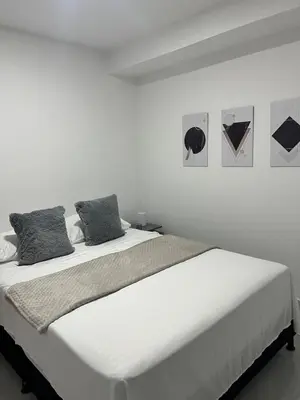 a white bedroom with a large bed with two pillows at Apartamento en La America 2 habitaciones in Medellín