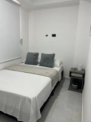 a white bedroom with two beds and a window at Apartamento en La America 2 habitaciones in Medellín