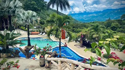 a resort swimming pool with palm trees and a mountain at Solvae EcoHotel in San Jerónimo