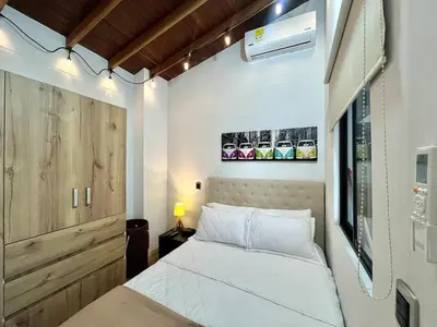 a small bedroom with a white bed and a wall at Suitable unique design with natural light Envigado in Envigado