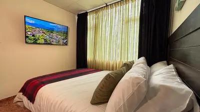 a bedroom with a bed with a television on the wall at Casa Boutique Familia Hurtado in Manizales