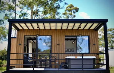 a tiny house with a deck with a table and chairs at Cabaña del lago con Jacuzzi in Rionegro