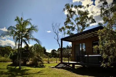 a small cabin in a field with a palm tree at Cabaña del lago con Jacuzzi in Rionegro