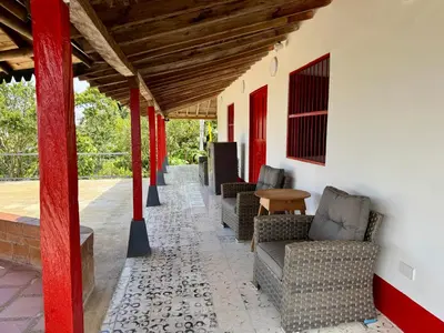 a porch with chairs and a table and red columns at Finca cafetera para descanso in Fredonia