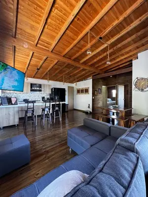 a living room with blue couches and a kitchen at Cabaña El Sueño de OPAD in Guarne